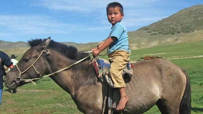 mongolian boy learning to ride horse