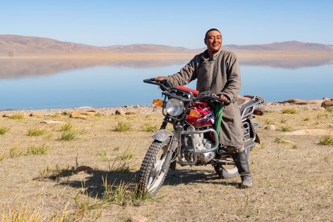 Mongolian man in a traditional deel sitting on a motorbike